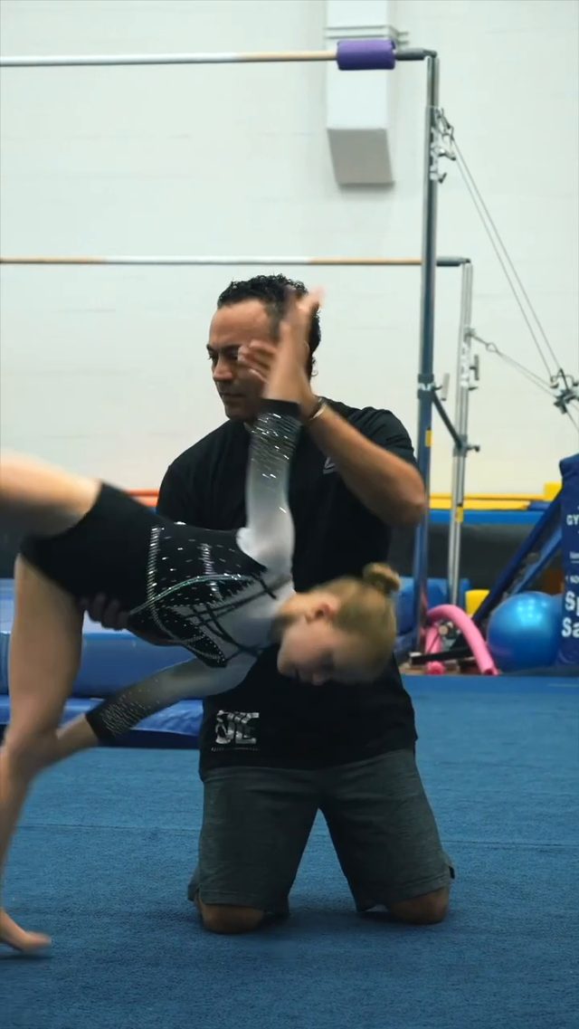 Coach Fuentes working one-on-one with a gymnast during a daytime session