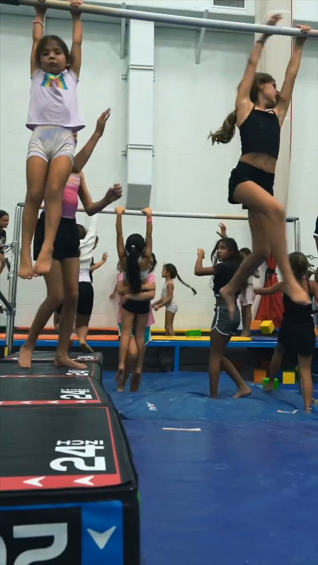 Young gymnasts hanging from the high bar at JLF Elite